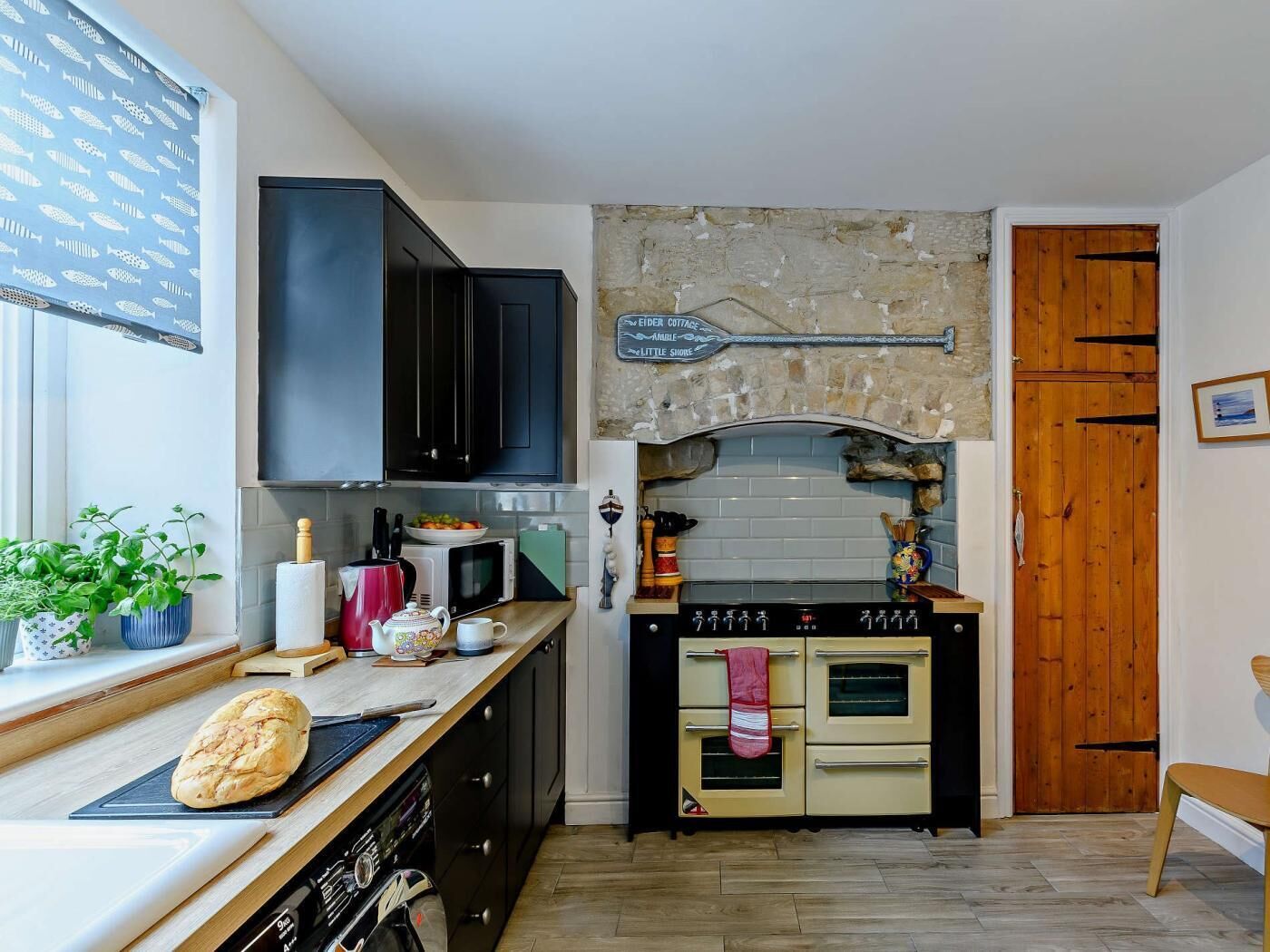 A compact kitchen with a stone backsplash, a wooden door, and a small dining area.