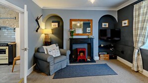 Ein Wohnzimmer mit einer Couch, Kamin, Fernseher und einer Steinwand.
