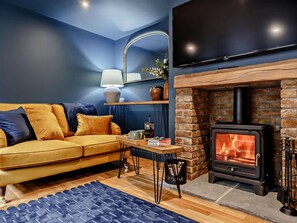 A living room with a sofa, a table, a fireplace, and a television. - 2 Bed in Leyburn (oc-93162) (Leyburn)