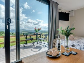 Ein Zimmer mit einem großen Fenster, einem Tisch mit Essen, einer Flasche und Gläsern.