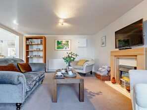 A living room with a sofa, a coffee table, a fireplace, a television, and a bookshelf. - 2 Bed in Torquay (oc-82540) (Torquay)