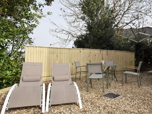 Une terrasse avec deux fauteuils, une table et des chaises.