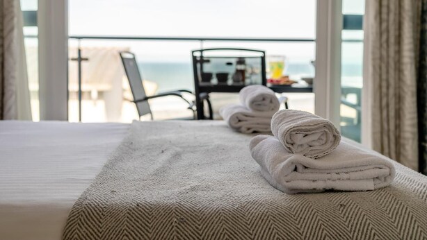 Een hotelkamer met een bed, een stoel en een tafel met handdoeken.