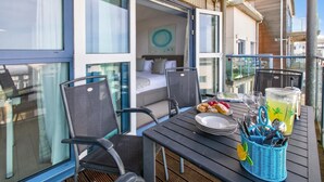 Een balkon met een ontbijttafel, een bed met uitzicht en een groot raam.