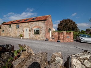 A stone building with a tiled roof, a car parked in front, and a stone wall with a plaque. - 1 Bed in Northallerton (oc-93792) (North Cowton)