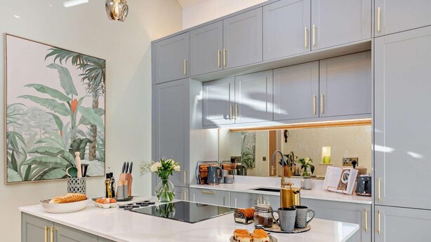 Een moderne keuken met grijze kastjes, een wit aanrechtblad en een groot eiland.