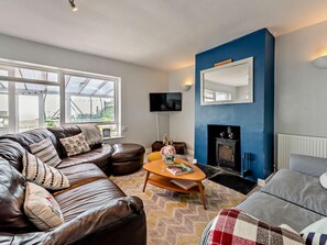 A living room with a leather sofa, a coffee table, a fireplace, and a television. - 3 Bed in Pevensey (oc-93829) (Normans Bay)
