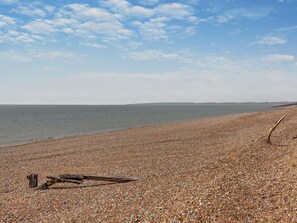 A pebbled beach with a wooden structure and a clear sky. - 3 Bed in Pevensey (oc-93829) (Normans Bay)