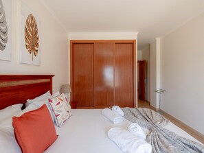 Ein Hotelzimmer mit einem Holzschrank, einem Bett mit Kissen, einer Decke und gerollten Handtüchern.