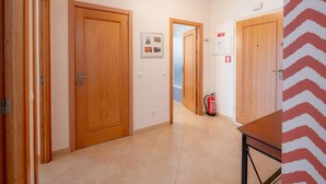 Ein Flur mit Holztüren, einem Feuerlöscher und einem gerahmten Bild an der Wand.
