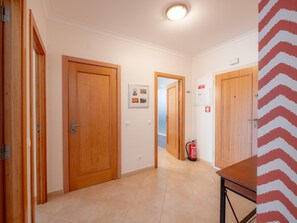A hallway with wooden doors, a fire extinguisher, and a framed picture on the wall. - Apt. Luz da Manhã, with sea views (Luz)
