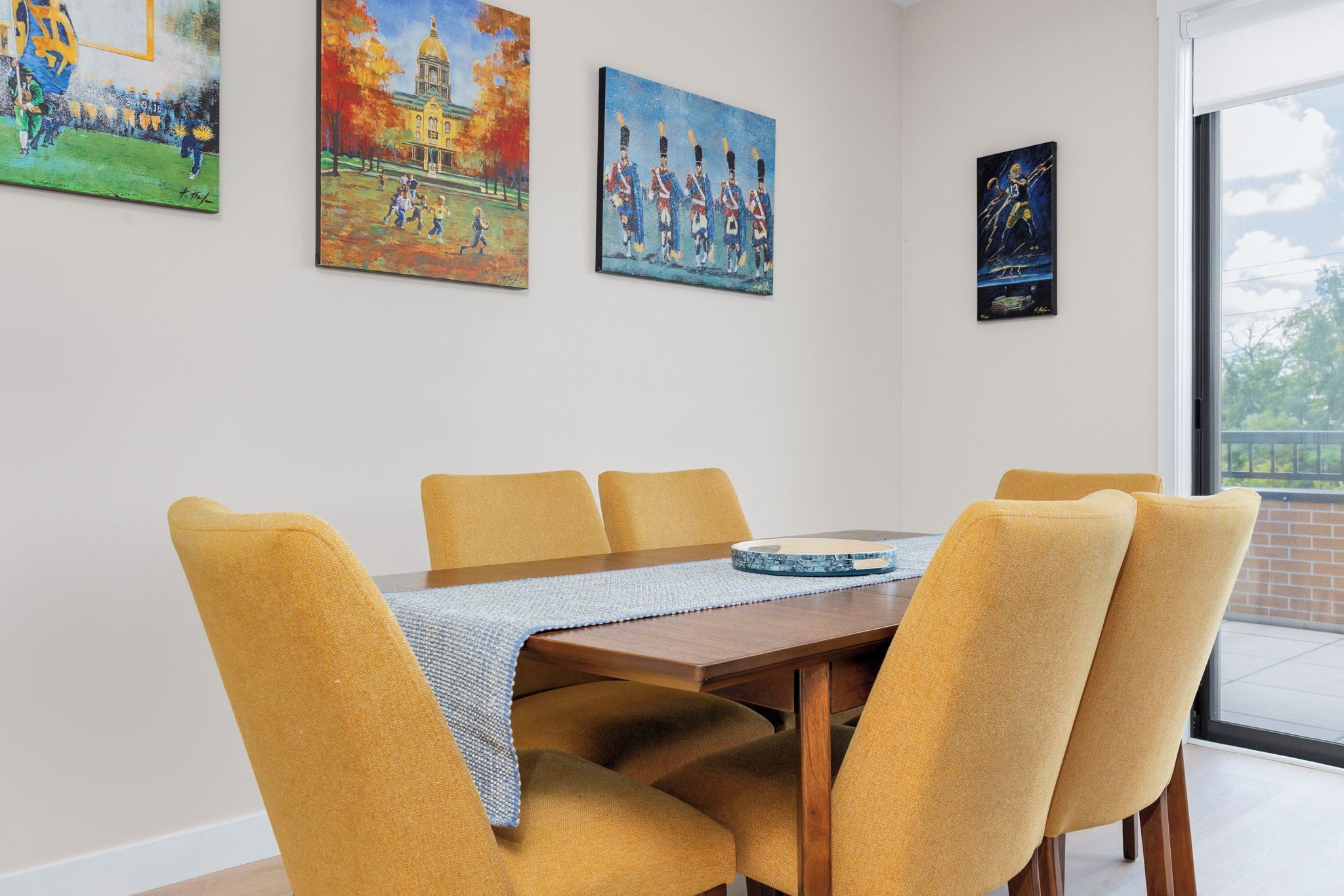 Un coin repas avec une table et des chaises, une fenêtre donnant sur un beau paysage et trois tableaux accrochés au mur.
