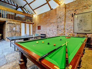 Ein Billardtisch mit Kugeln und Spielstöcken, ein Tischtennis-Tisch und eine Karte an der Wand.