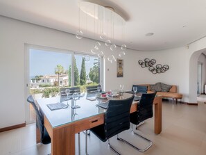 A modern dining area with a glass table, black chairs, and a view of the sea. - Casa Vista Linda | Private Sea View Villa & Saltwater Pool (LUZ-LGS)