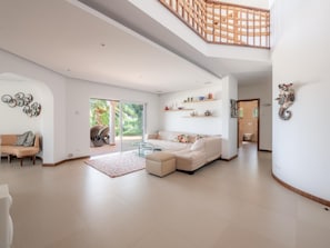 A spacious living area with a large sofa, a glass coffee table, and a staircase leading to an upper level. - Casa Vista Linda | Private Sea View Villa & Saltwater Pool (LUZ-LGS)