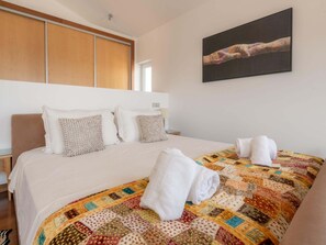 Une chambre d’hôtel avec un grand lit, une couette et un tableau au mur.