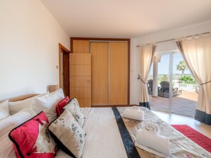 A bedroom with a bed, a wardrobe, and a balcony with outdoor furniture. - Casa Vista Linda | Private Sea View Villa & Saltwater Pool (LUZ-LGS)
