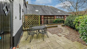 A courtyard with a table and chairs, a wooden fence, and a building with a sloped roof. - 2 Bed in Doncaster (oc-93770) (Mattersey)