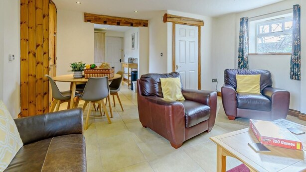 A living room with leather sofas, a dining table with chairs, a kitchen area, and a window with curtains. - 2 Bed in Doncaster (oc-93770) (Mattersey)