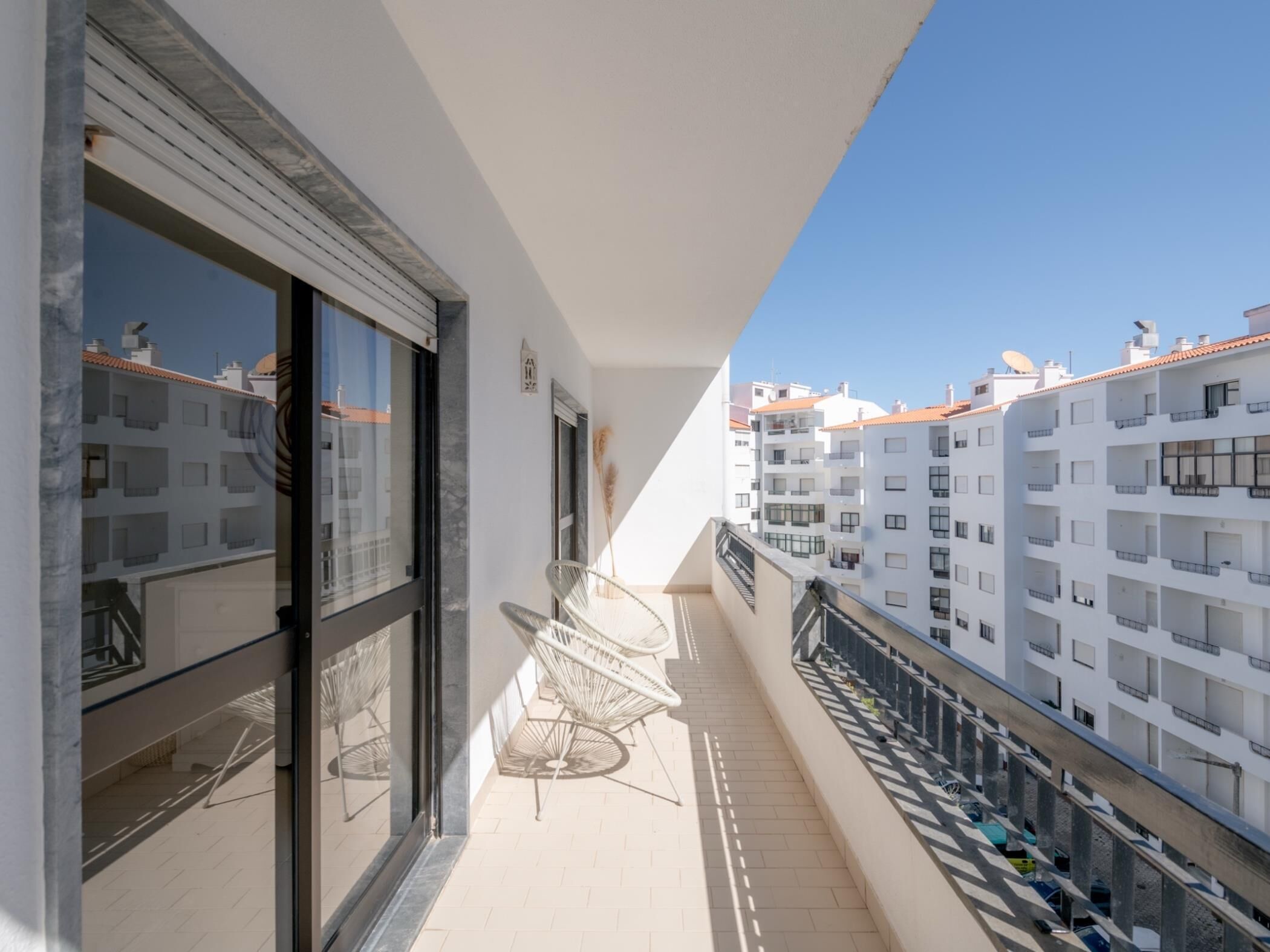 A balcony with a chair, a window, and a view of adjacent buildings.
