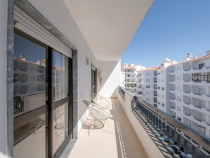 Ein Balkon mit Stuhl, Fenster und Blick auf angrenzende Gebäude.