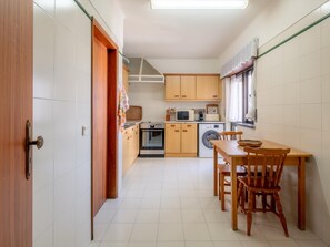 A compact kitchen with wooden cabinets, a dining table, and chairs. - Lagos Urban Hideout: Discover your own little city retreat in the heart of Lagos (Lagos)