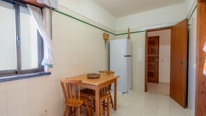A compact kitchen with a dining table, chairs, a refrigerator, and a window with curtains. - Lagos Urban Hideout: Discover your own little city retreat in the heart of Lagos (Lagos)