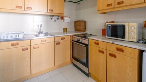 A kitchen with wooden cabinets, a sink, a microwave, and an oven. - Lagos Urban Hideout: Discover your own little city retreat in the heart of Lagos (Lagos)