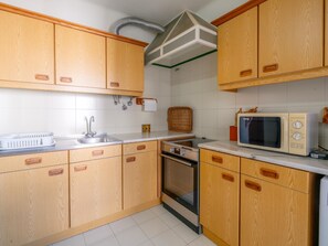 Eine Küche mit Holzausstattung, einem Spülbecken, einer Mikrowelle und einem Backofen.