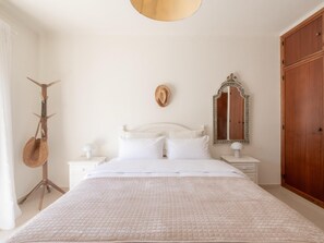 Ein Schlafzimmer mit einem Bett, zwei Nachttischen, einem Spiegel und einem Kleiderschrank.