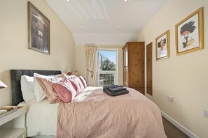 A bedroom with a bed, a nightstand, a window with curtains, and framed artwork on the walls. - 1 Bed in Sturminster Newton (oc-93841) (Hazelbury Bryan)