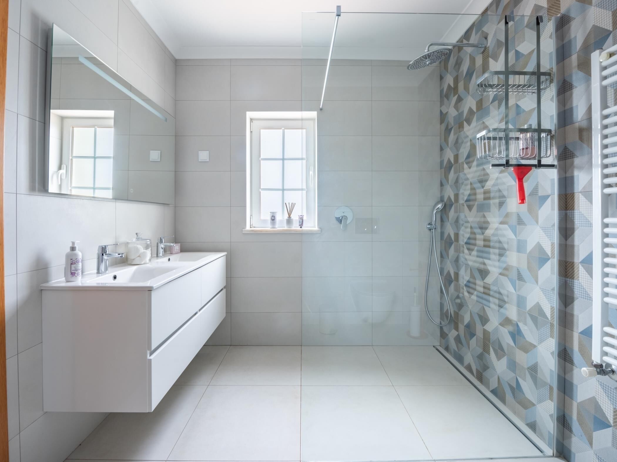Une salle de bain moderne avec une douche à parois de verre, un meuble-lavabo avec un miroir et une fenêtre.