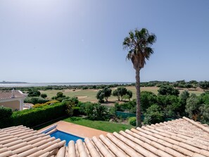 A pool with a view of the sea, a palm tree, and a golf course. - Villa Sea La Vie | Exclusive Villa with Private Pool near Palmares Golf Course (Vale da Lama - Odiáxere)