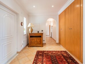 Un couloir avec une armoire en bois, un tapis rouge à motifs et une grande porte en bois.