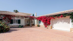 A house with a paved driveway, a garage, and a small tower-like structure in the background. - Villa Sea La Vie | Exclusive Villa with Private Pool near Palmares Golf Course (Vale da Lama - Odiáxere)