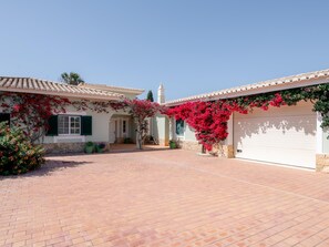 A house with a paved driveway, a garage, and a small tower-like structure in the background. - Villa Sea La Vie | Exclusive Villa with Private Pool near Palmares Golf Course (Vale da Lama - Odiáxere)