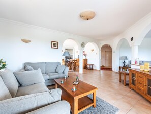 A spacious living area with a grey sofa, wooden coffee table, and a dining area with a table and chairs. - Villa Sea La Vie | Exclusive Villa with Private Pool near Palmares Golf Course (Vale da Lama - Odiáxere)
