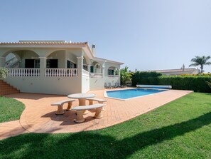 A house with a swimming pool, a patio with a table and chairs, and a well-maintained lawn. - Villa Sea La Vie | Exclusive Villa with Private Pool near Palmares Golf Course (Vale da Lama - Odiáxere)