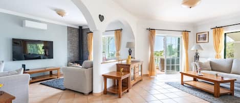 A spacious living room with a fireplace, a television, and a balcony with curtains.