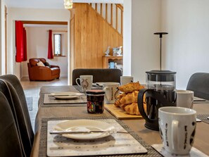 Un coin repas avec une table mise pour le petit-déjeuner, comprenant des croissants, du café et une machine à café.