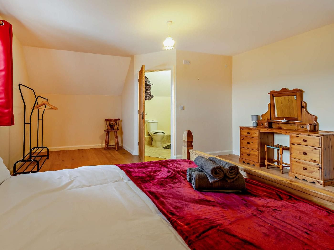 Une chambre à coucher avec un lit, une commode, un miroir et une chaise.
