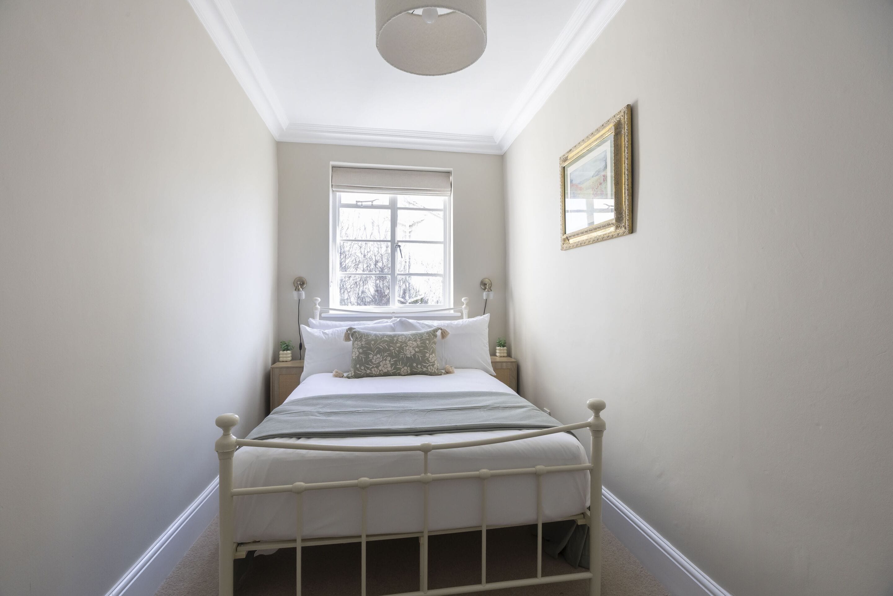 Un dormitorio con una cama individual, una ventana, una mesita de noche y un cuadro enmarcado en la pared.