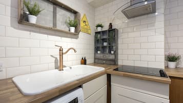 A modern kitchen with a white sink, stainless steel faucet, and a built-in oven.