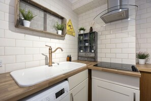 A modern kitchen with a white sink, stainless steel faucet, and a built-in oven. - Stylish Two Bed Apartment on Montpellier Spa Road (Cheltenham)