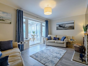 A living room with a sofa, a coffee table, a rug, and a painting on the wall. - 3 Bed in Swanage (oc-93866) (Swanage)