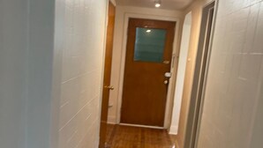 A narrow hallway with wooden flooring and white walls.