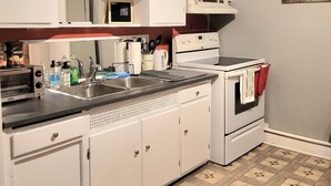 A kitchen with white cabinets, a stove, a microwave, and a sink.