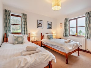 A double room with two beds, a radiator, a window with curtains, and framed pictures on the wall. - 3 Bed in Keswick (oc-93883) (Braithwaite)