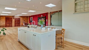 Una cocina amplia con una isla central, armarios de madera y una zona de comedor con una silla.
