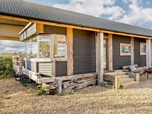 A modern house with a large glass window, wooden deck, and a gravel driveway. - 2 Bed in Lutterworth (oc-93762) (Laughton)